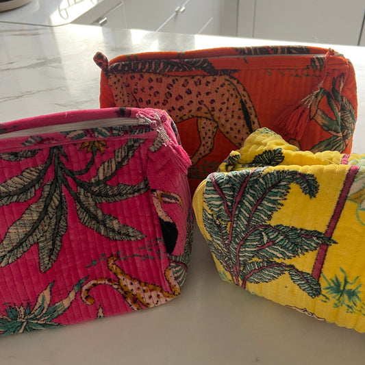 Three block printed velvet cosmetic bags in bright colors, placed side by side.